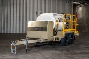 Front-side angle of the VX2000 Commander Heritage hydromulcher, highlighting the enclosed engine compartment, heavy-duty tow hitch, and streamlined tank design.