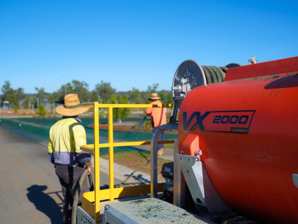 How much does a Hydroseeder Cost? | Hydroseeder Price Guide 2 Contractors with a hydroseeder and spraying hydroseed in the background for the 'How much does a hydroseeder Cost?' Article.
