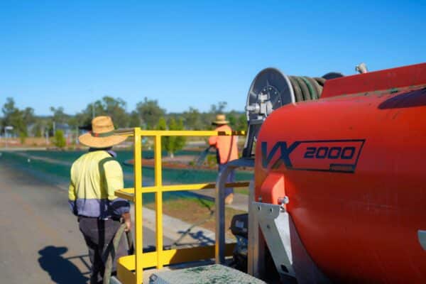 Contractors with a hydroseeder and spraying hydroseed in the background for the 'How much does a hydroseeder Cost?' Article.
